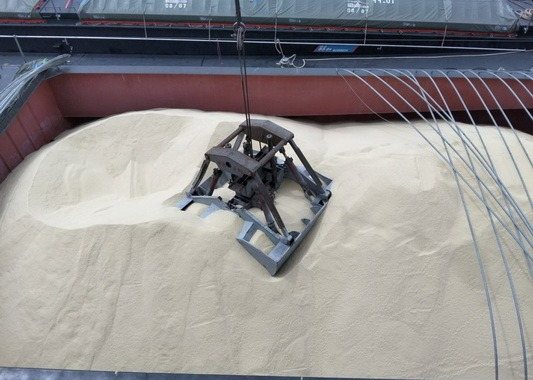 Grab bucket resting on bulk cargo in a ship’s hold