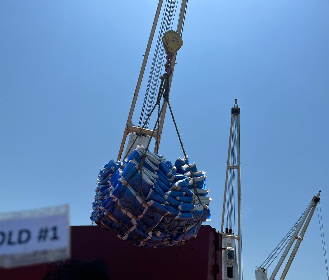 Hand-held hold number board in front of a sling of bagged cargo